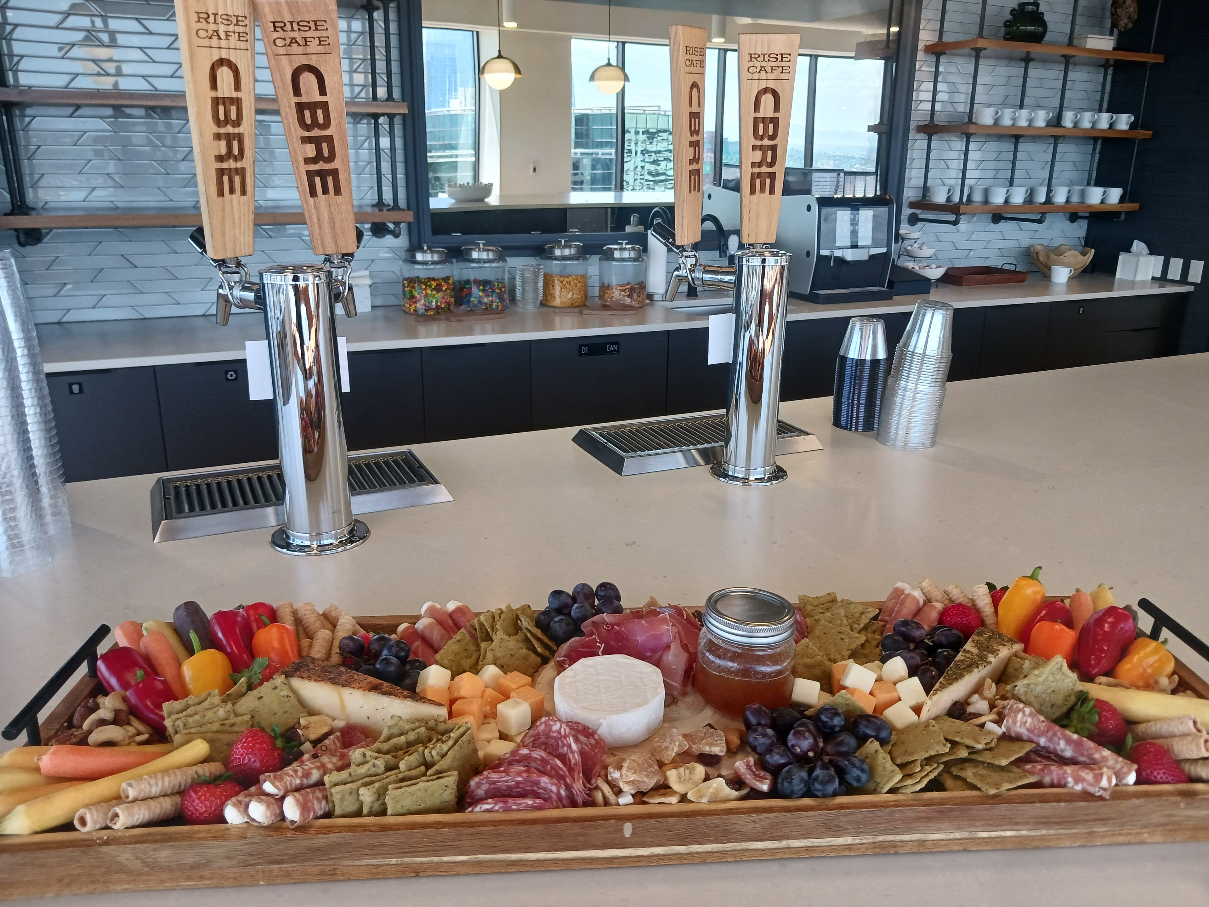 Grazing board on a corporate cafe counter with assorted meats, cheeses, fruit, and crudité