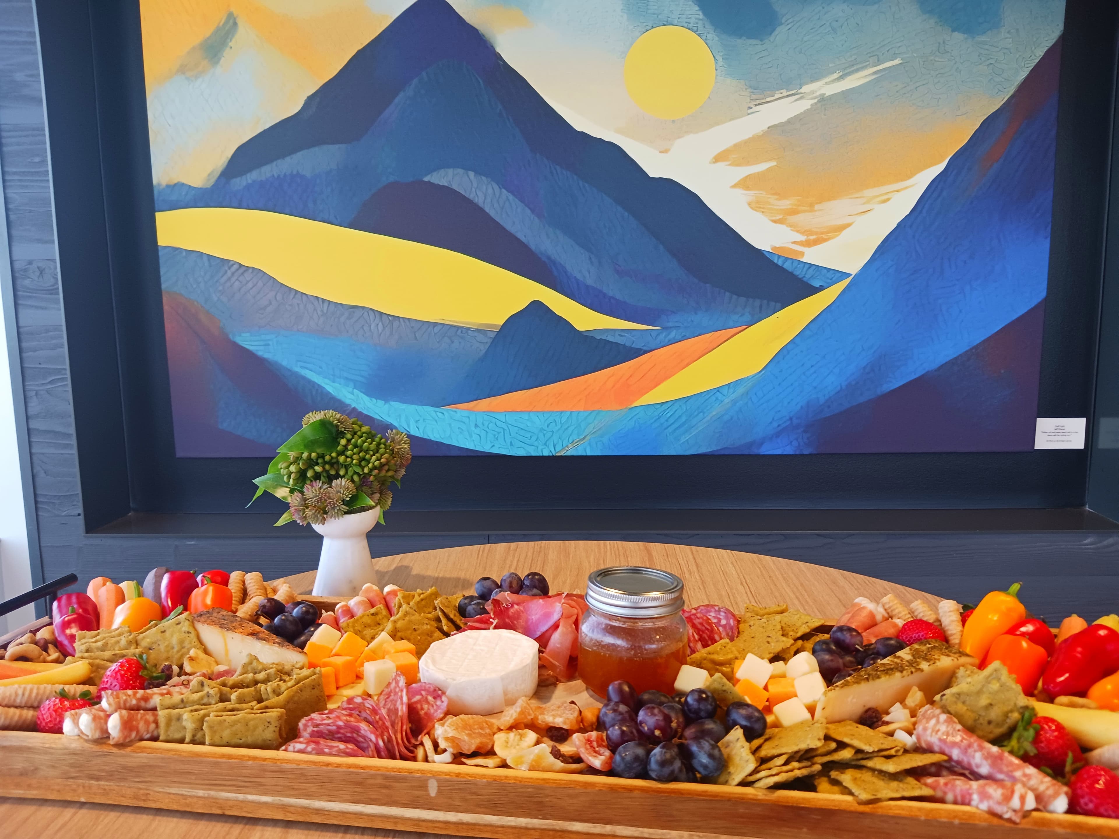 Charcuterie grazing board with brie, salami, grapes, peppers, and honey